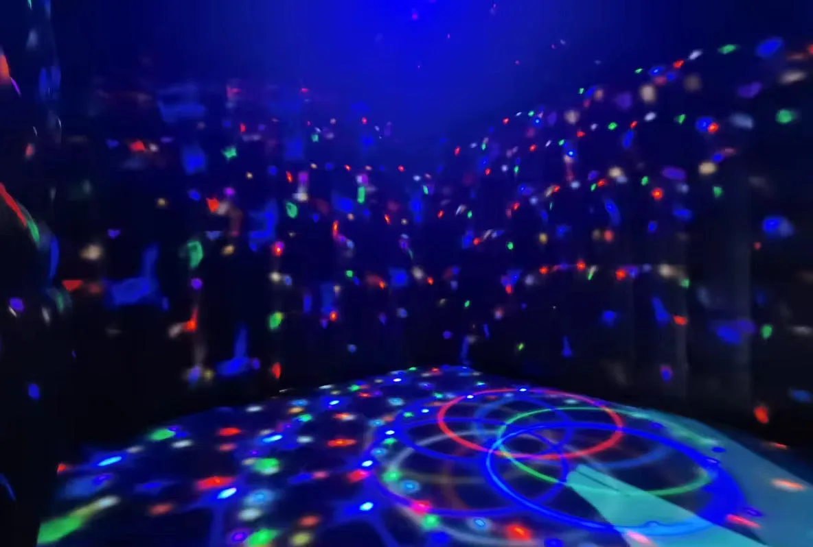 Inside an inflatable nightclub tent with disco lights across the floor and walls